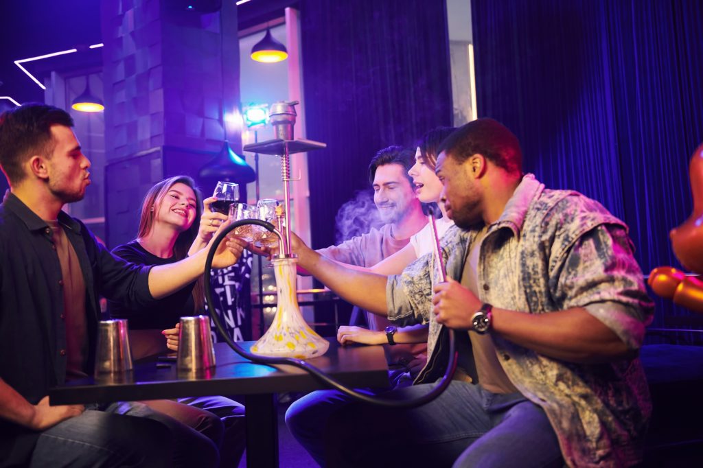 Smoking hookah. Group of friends having fun in the night club together