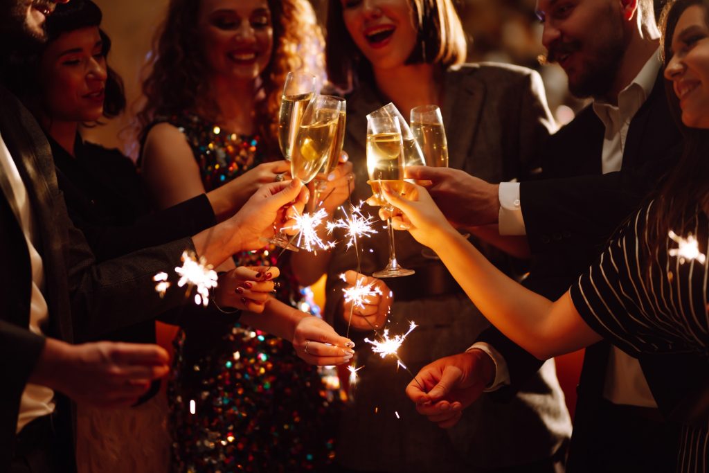 Sparkling sparklers in hands. Playing firework to celebrate winter holidays with friends at party