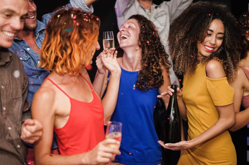 Young multiracial friends dancing at home private party - Focus on african girl hands holding bottle